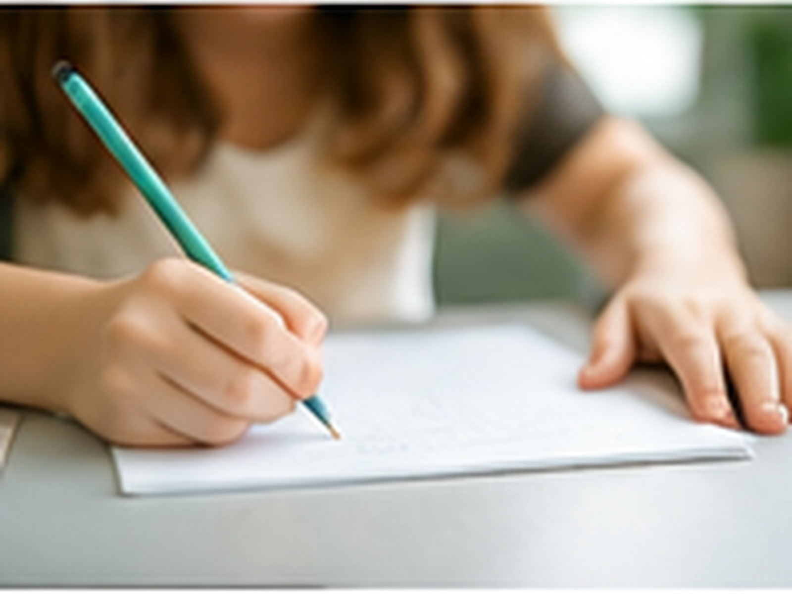 Child practising handwriting with a pencil at a desk